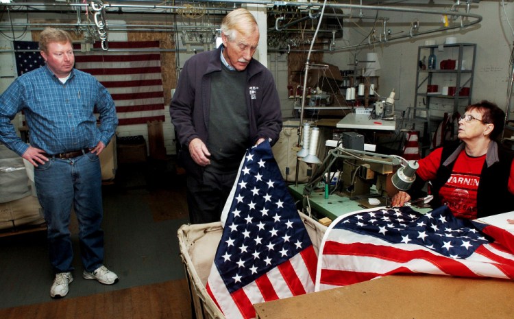 U.S. Sen. Angus King, I-Maine, center, examines an American flag sewn by Maine Stitching Specialties employee Charlene Goodrich as owner Bill Swain conducts a tour of the Skowhegan company on Tuesday.