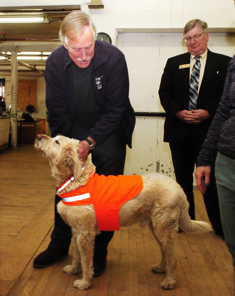 U.S. Sen. Angus King, I-Maine, pets Maine Stitching Specialties mascot dog Max, wearing a company safety dog vest, during a tour of the Skowhegan company on Tuesday. Ben Tucker is at right.