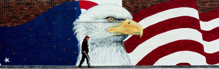 Skowhegan Village plaza owner Dana Cassidy inspects a large mural showing an American flag and an eagle being painted Thursday outside the Maine Veterans Museum, which is under construction in Skowhegan.
