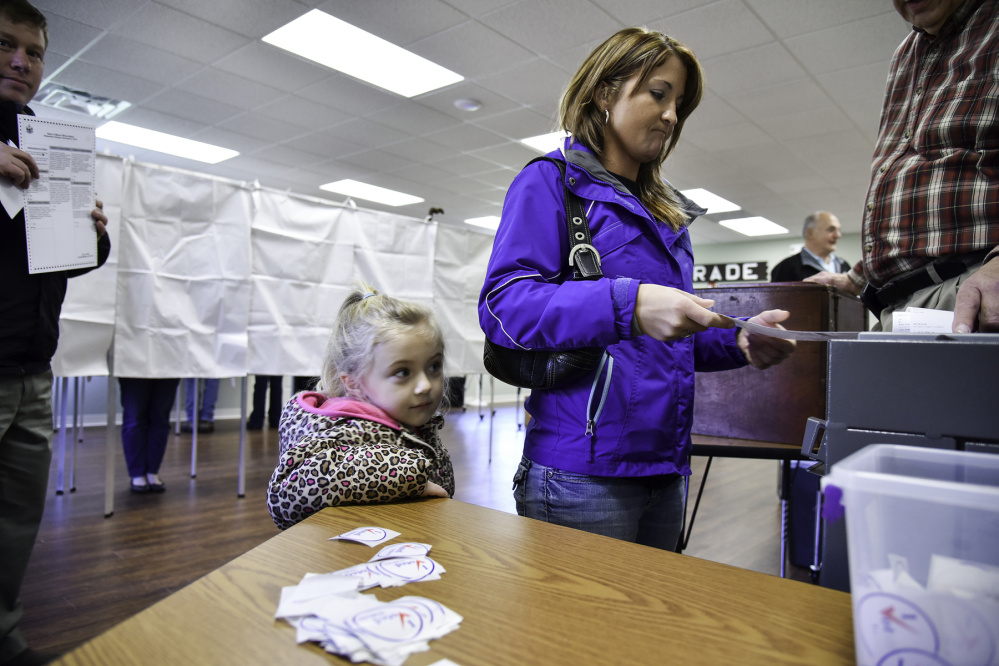 Hailey Jones watches her mother, Tanya, casting a ballot at the Belgrade Town Hall.