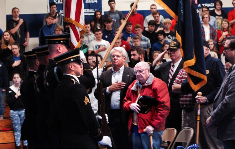 World War II veterans George Prentiss, of Fairfield, front, and Steve Ball join Erskine Academy students and staff members Tuesday in a color guard posting of flags during a salute to veterans for the upcoming Veterans Day holiday at the South China school.