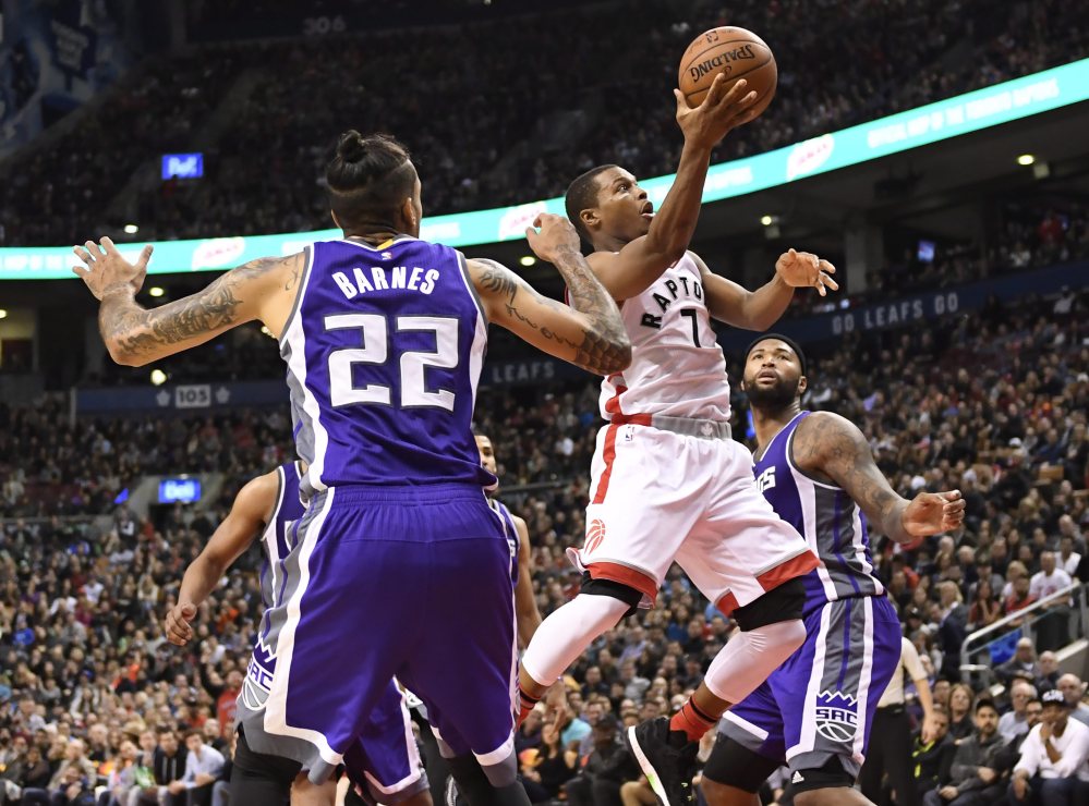 Toronto Raptors guard Kyle Lowry (7) goes for a layup past Sacramento  forward Matt Barnes (22) and center DeMarcus Cousins during second half of a game Sunday.
