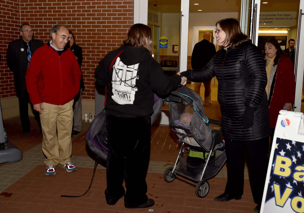 Emily Cain, right, greets a voter as Rep. Bruce Polquin, left, watches nearby Tuesday evening outside the Cross Insurance Center in Bangor, where voters were casting ballots. Poliquin, the incumbent Republican congressman, was up against Cain, a Democrat, in a rematch of their 2014 contest.