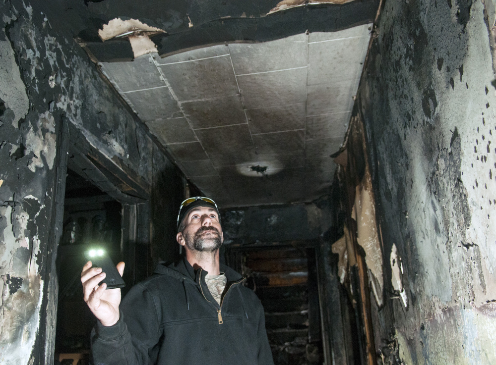 Jeffrey Sansouci shows the location of the smoke alarm that woke him Saturday before a fire destroyed his Randolph home.