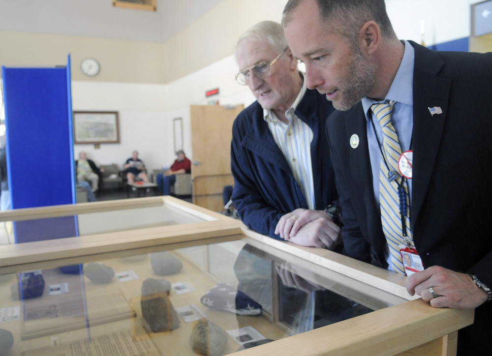 Veteran Peter Ogden, left, and Togus VA Director Ryan Lilly and examine stones on display Thursday at the Togus veterans hospital as part of the Summit Project. The engraved rocks commemorate military veterans who have died since Sept. 11, 2001.
