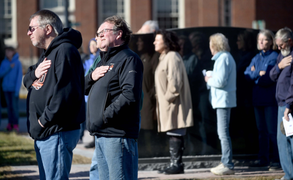 People listen to the National Anthem on Friday during a re-dedication of the Veterans Memorial Park in Skowhegan.