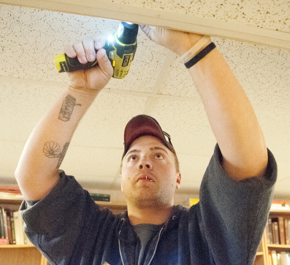 Randolph firefighter Nicholas Kimball installs a smoke detector on Saturday in a Randolph home.