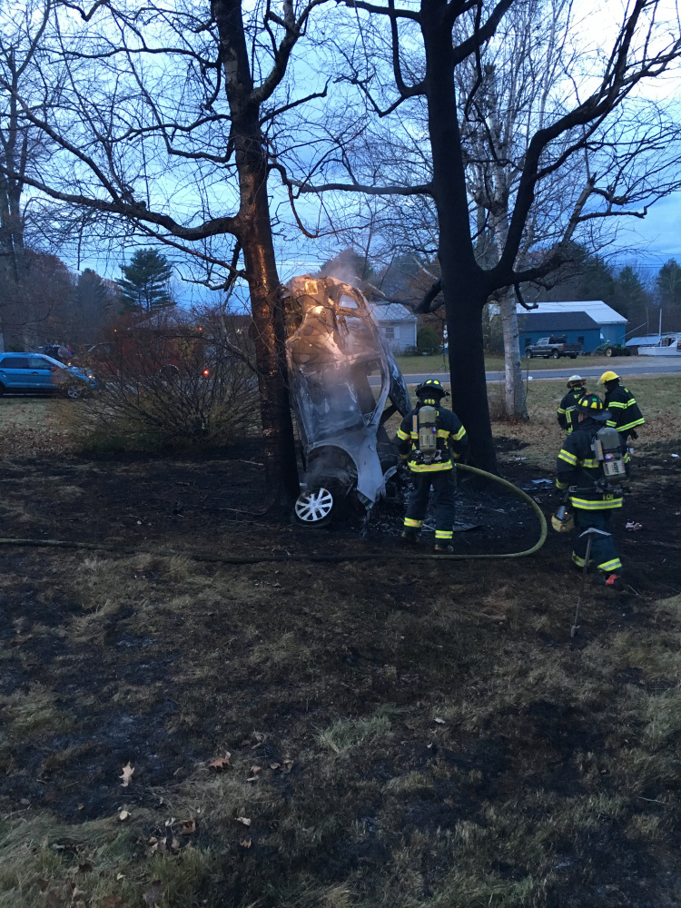 West Gardiner firefighters douse the remaining flames in an overturned burning sport-utility vehicle Sunday near the intersection of High Street and Hallowell-Litchfield Road in West Gardiner. The vehicle caught fire after striking a tree about 6 a.m. while its driver was on his way to work.