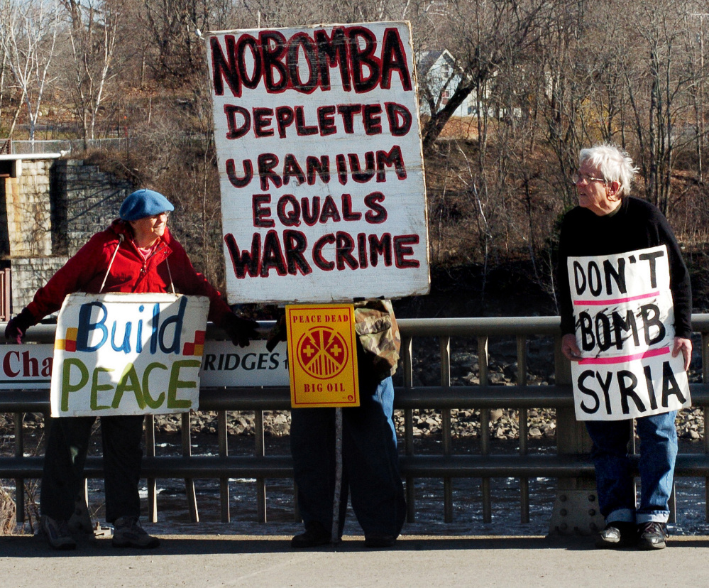 War protesters Lynne Harwood and Mark Roman hold signs Sunday on the Margaret Chase Smith bridge in Skowhegan.