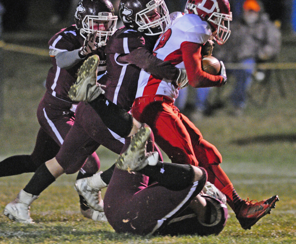 MCI defenders Clark Morrison, left, Adam Bertrand and Seth Bussell wrap up a Dexter running back during the Little Ten Conference championship game Friday night at Alumni Field in Pittsfield.