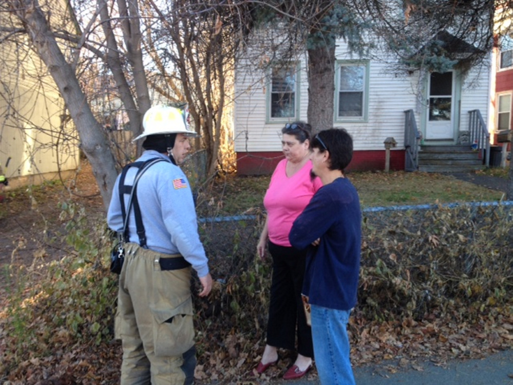 Waterville fire Captain John Gromek (left) tells Cheryl Jack that her cat is OK and escaped a fire Saturday afternoon at the apartment building she lives in on Front Street in Waterville. At right is her next door neighbor, Jeffrey Mello.