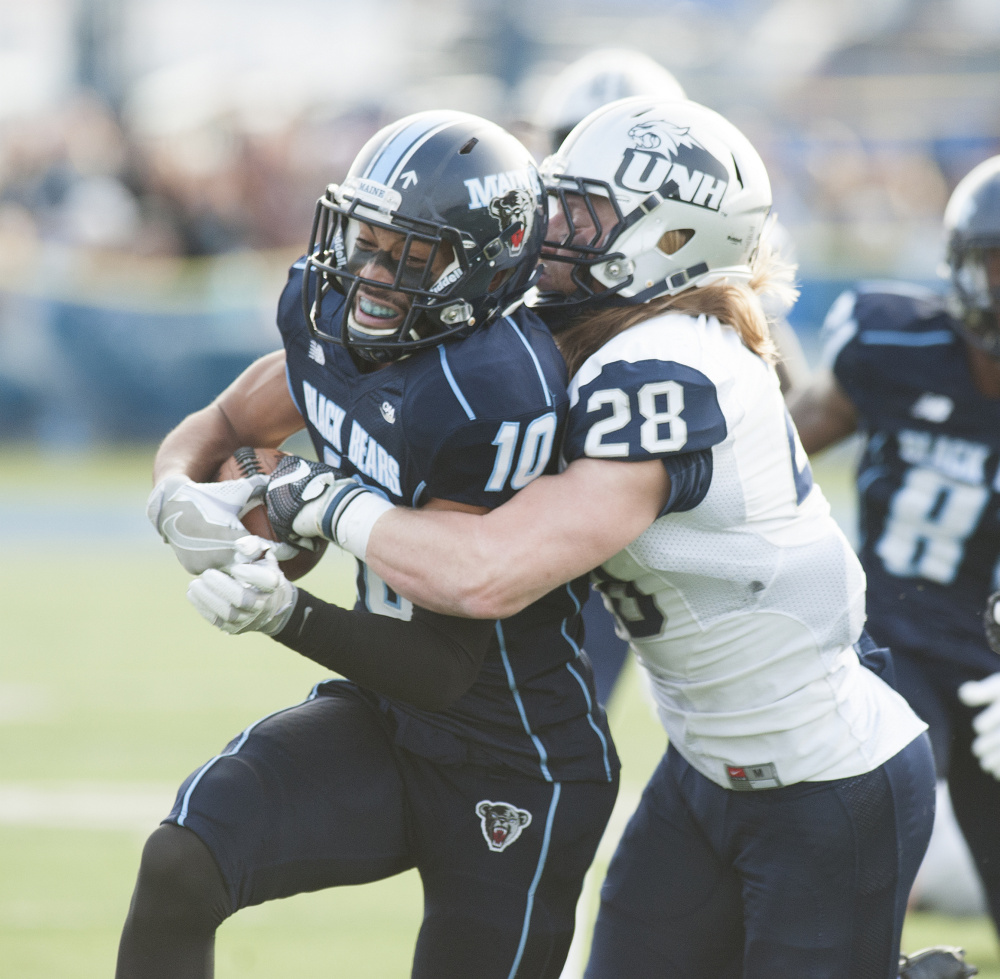 UMaine's Micah Wright can't escape the grasp of UNH defender Zaire Williams during the first half of a pivotal regular season finale for both teams Saturday in Orono. The Wildcats won 24-21 to end Maine's season.