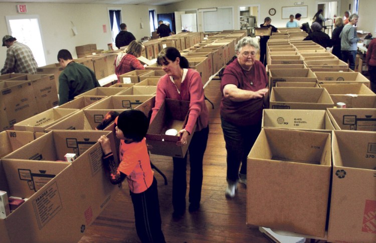Volunteers fill nearly 200 Thanksgiving food boxes at the Federated Church in Skowhegan on Monday. Betsy Drumm, right, president of the church women's fellowship, fills boxes as Heather Johnson and her son John work together.