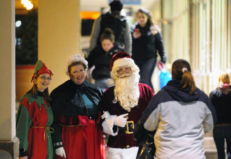 An elf accompanies Mrs. Claus and Santa Claus as they greet shoppers walking between stores Nov. 27, 2015 — which was Black Friday — at the Marketplace at Augusta in Augusta.