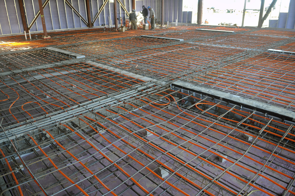 Workers install radiant heating beneath the bays last week at the new fire station in Augusta.