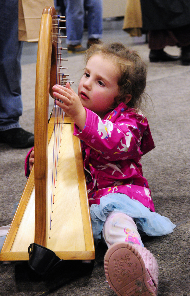Dalais Belyeu, 3, of Albion, tries out a harp made and being offered for sale by Mellori Worthen during a craft show Saturday at the Augusta Civic Center.
