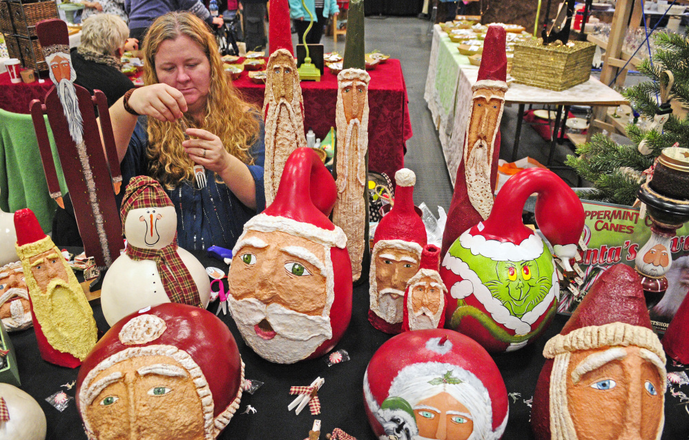 Sitting behind a display of her painted gourds, Jessica Howarth, of Howard Hand Crafted in Vassalboro, ties a string on a painted Santa fork ornament while waiting for customers during a craft show Saturday at the Augusta Civic Center.