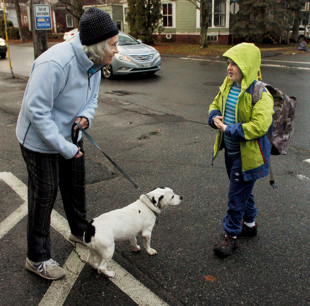 Cindy Longstaff and her dog, Wilbur, greet Albert S. Hall School student Nat Minot as he arrives for school in Waterville on Monday. Longstaff and Wilbur have met kids as they arrive on buses for four years, and 10-year-old Nat even wrote a poem about the friendly dog.