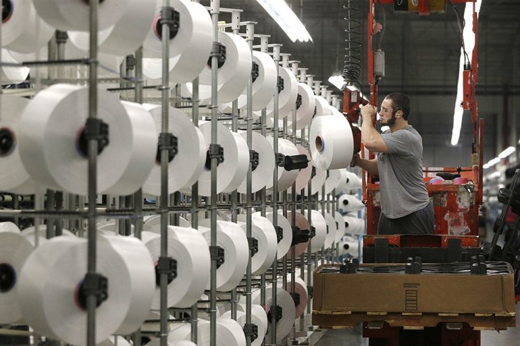 A worker loads spools of thread at the Repreve Bottle Processing Center, part of the Unifi textile company, in Yadkinville, N.C. Over the past six years, Unifi has added about 200 jobs, bringing the total to over 1,100.