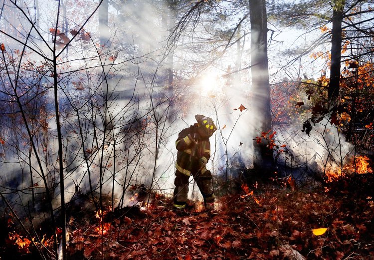 Jeremy Dowd, an intern at the Scarborough Fire Department, battles a brush fire along the railroad tracks near Highland Avenue and Black Point Road on Friday afternoon.