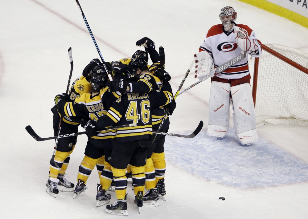 Carolina goalie Cam Ward watches as Bruins players celebrate the game-tying goal by defenseman Torey Krug (47) with seconds to go in the third period of Thursday night's game in Boston. The Bruins won, 2-1, in a shootout.