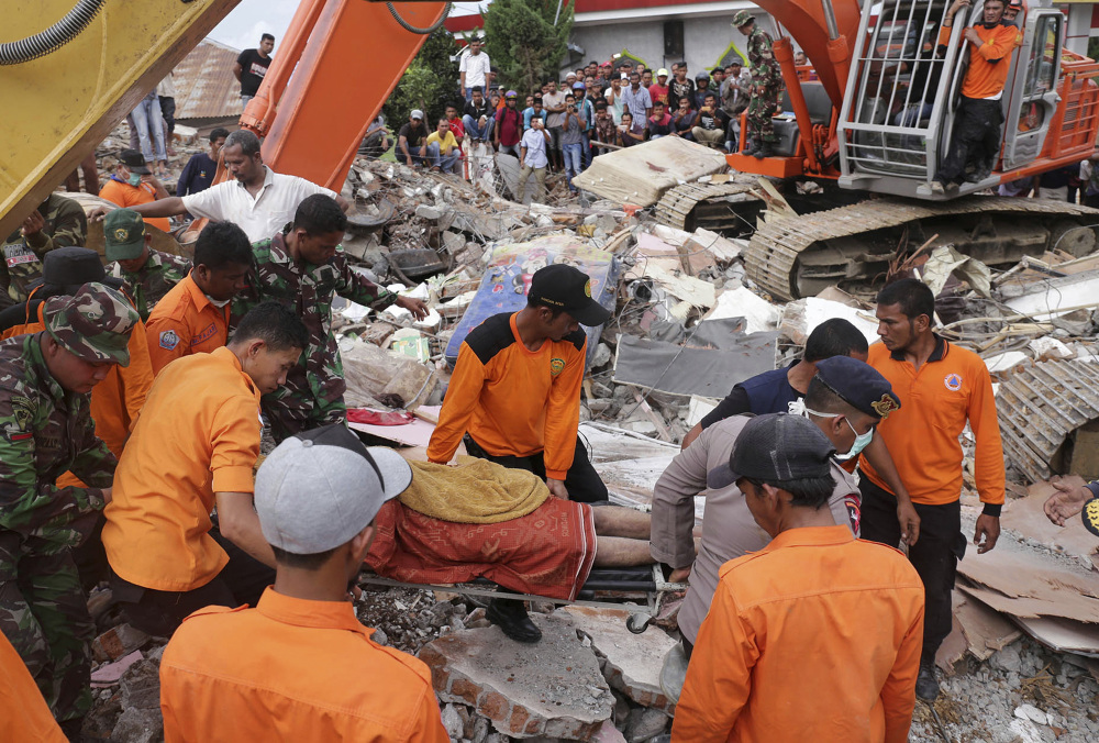 Rescuers recover a victim from the rubble of a collapsed building after an earthquake in Pidie Jaya, Aceh province, Indonesia, on Wednesday. A strong earthquake rocked Indonesia's Aceh province early on Wednesday, killing a large number of people and sparking a frantic rescue effort in the rubble of dozens of collapsed and damaged buildings.