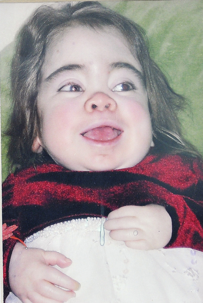 A photograph of Delaney Fuller is displayed on a table near the new stained-glass tree created by Maine artist Laura Fuller in memory of her daughter, who spent a lot of time at the Bush children's hospital before she died at age 9.