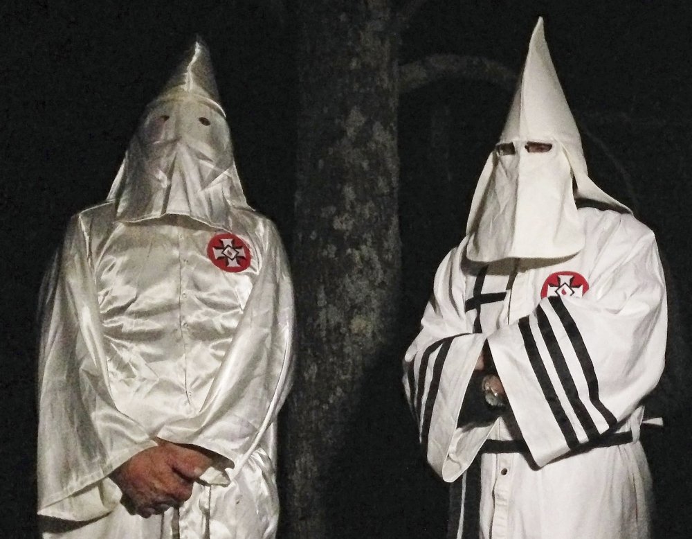 Two masked Ku Klux Klansmen stand on a muddy dirt road during an interview near Pelham, N.C. The KKK and other white extremist groups are eschewing the term "white supremacist" in an attempt to mainstream their racist beliefs.