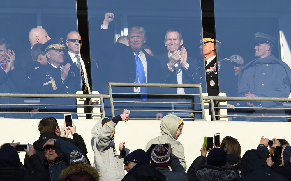 President-elect Donald Trump waves to the crowd from a suite at M&T Bank Stadium in Baltimore Saturday afternoon during the 117th annual Army-Navy football game.