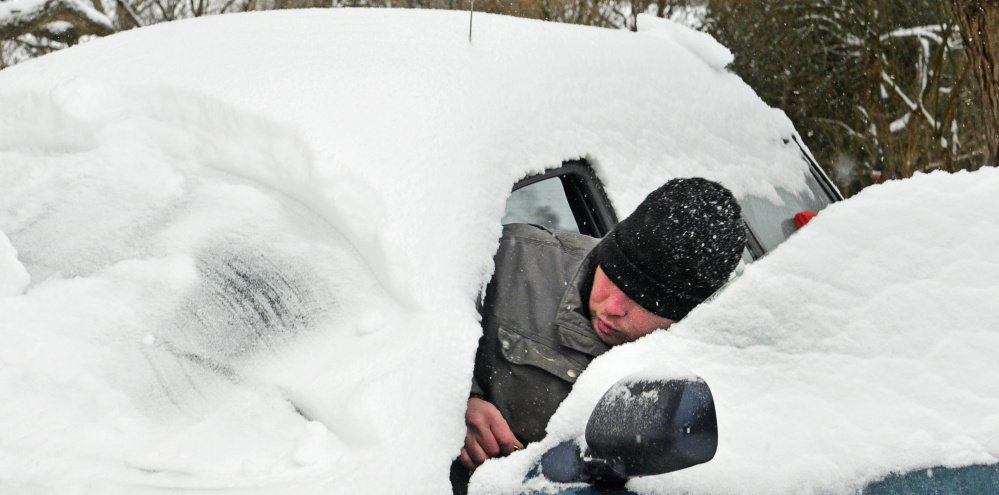 HALLOWELL, ME - DEC. 12: John Rosa climbs in to start his car while cleaning it off during the first big snowstorm of the season on Monday Dec. 12, 2016 in Hallowell.
