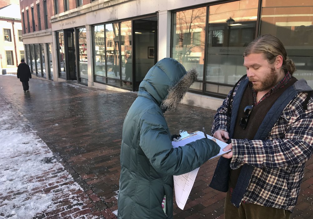 Tina Kartika, 24, of Portland signs a petition Tuesday to put Medicare expansion on the Maine ballot. George Frangoulis of Portland, working for the Maine People's Alliance, was gathering signatures in Monument Square.
