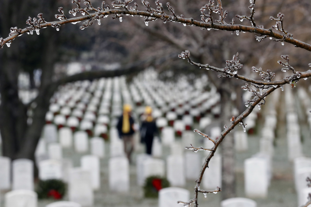 Ice is seen on trees as volunteers place wreaths at graves during Wreaths Across America at Arlington National Cemetery, Saturday, Dec. 17, 2016 in Arlington, Va. Organizers estimate more than 245,000 wreaths were placed at graves throughout the cemetery. (AP Photo/Alex Brandon)
