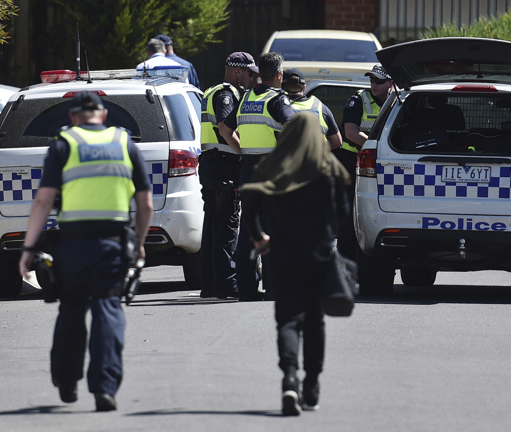 Police accompany a woman at the scene where a house was raided at Meadow Heights in Melbourne, Australia on Friday. Police in Australia detained five suspects who were allegedly planning a series of Christmas Day bomb attacks.