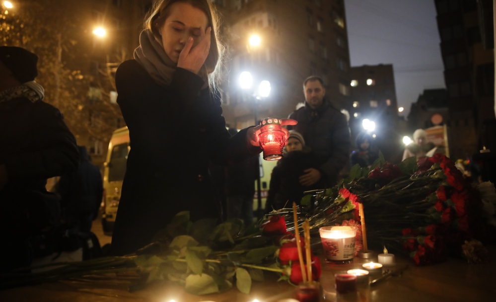 A woman lights a candle at the Alexandrov Ensemble's building in Moscow on Sunday, at a memorial set up after a plane carrying 64 members of the renowned military choir crashed into the Black Sea after taking off from Sochi.