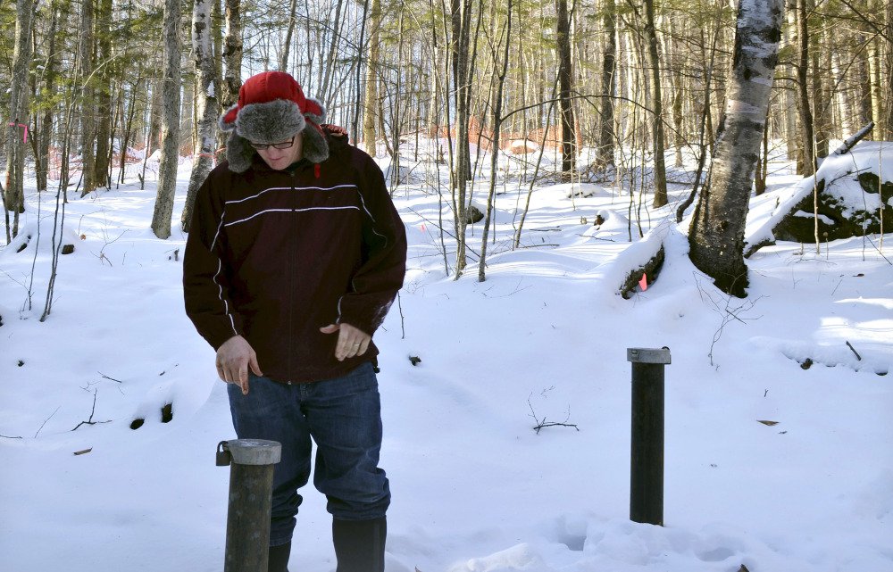 Richard Higgins, whose family's well water has been contaminated by a suspected carcinogen from a Dartmouth College dump site, looks down at one of many test wells installed to monitor the groundwater in Hanover, N.H.