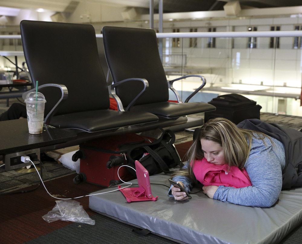 Chelsey Kalmback plays on her phone while waiting for a flight to North Dakota after flights were delayed or canceled Monday at Minneapolis-St. Paul International Airport.