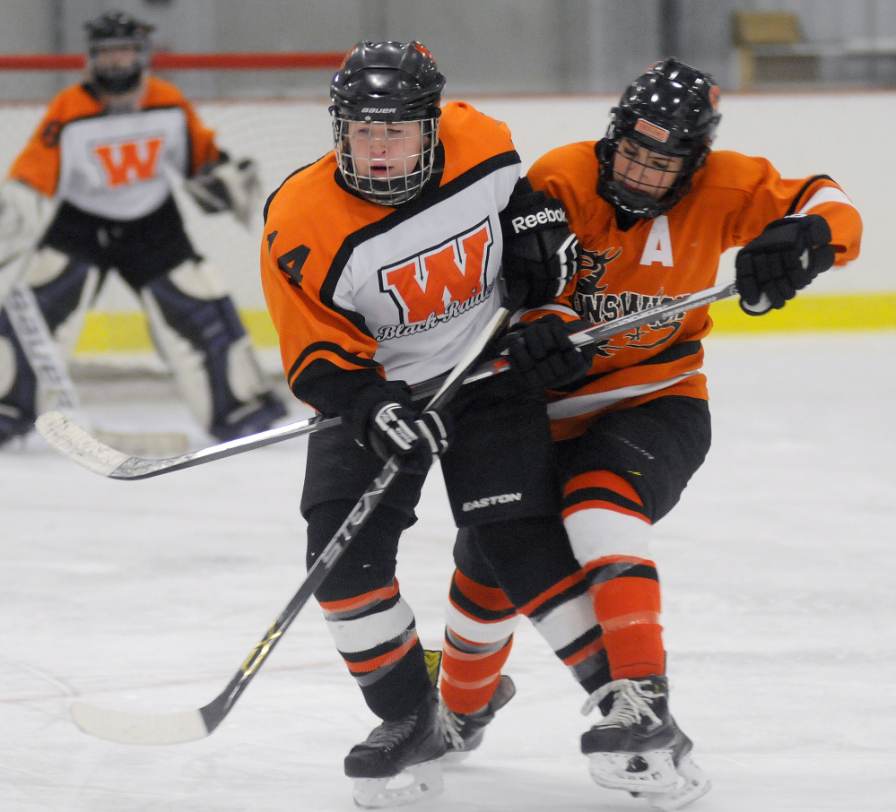 Gardiner/Winslow's Julia Hinkley, left, skates through a check from Brunswick's Jenna Brooks during a girls hockey game Wednesday night at Bonnefond Ice Arena in Kents Hill.