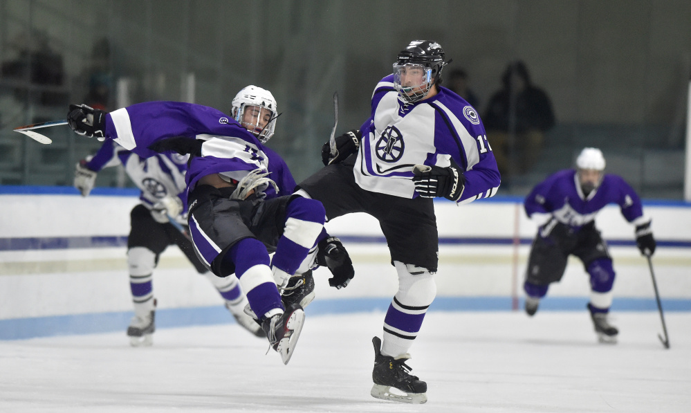 Waterville Senior High School's Zach Smith, right, knocks Hampden Academy's Marcus Dunn to the ice in the first period Saturday night at Colby College's Alfond Rink.