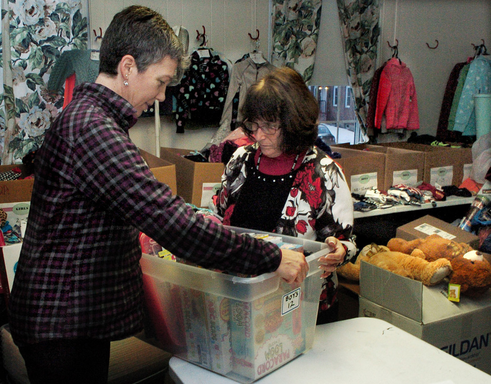 Volunteers Sarah Leblanc, left, and Debbie Plummer fill containers with clothes and toys for children at the Maine Children's Home for Little Wanderers in Waterville on Tuesday.