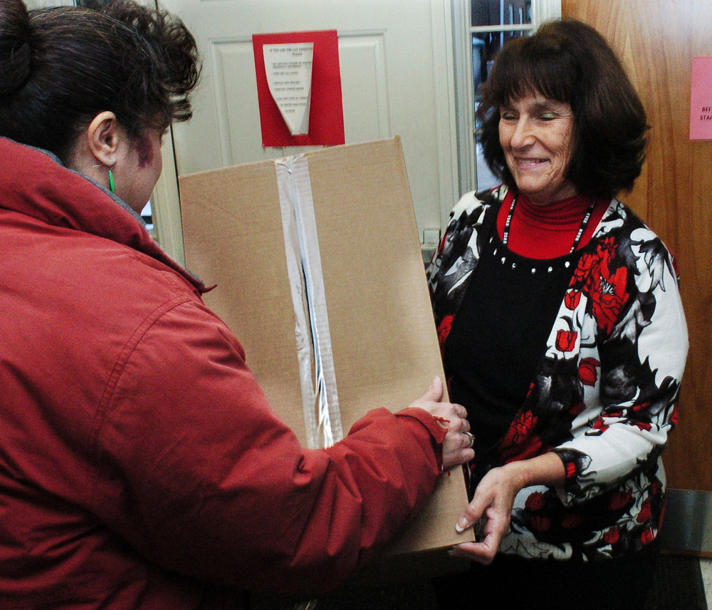 Volunteer Debbie Plummer, right, hands a box with children's gifts and clothes to a recipient who asked not to be identified by name at the Maine Children's Home for Little Wanderers in Waterville on Tuesday.