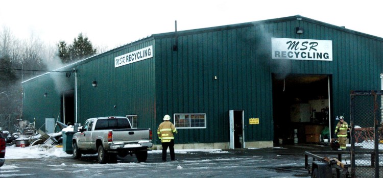 Smoke billows out from the MSR Recycling building as Winslow firefighters assemble fans to clear the area after it was extinguished on Tuesday.
