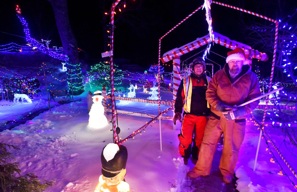 Donald Lagasse, back left, and Ric Spaulding, right, stand on Thursday among the many thousands of lights on display at their homes, also know as the China Road Christmas Park, on China Road in Winslow.