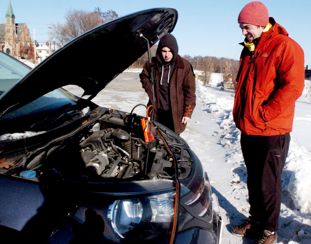 As the temperature falls below zero Friday morning, Colin Finn, left, and Charles Gauvin anxiously wait for the car battery to charge while getting a boost at Head of Falls in Waterville.