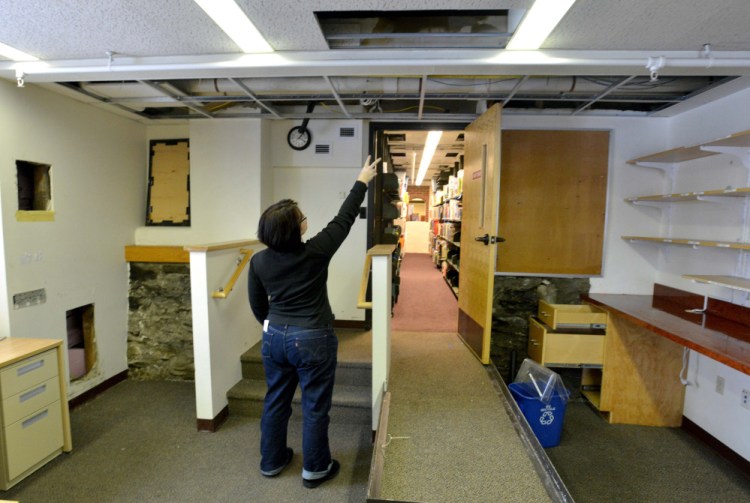 Tammy Rabideau, assistant director at the Waterville Public Library, points to the pipe that broke over night that damaged books and computers in Waterville on Saturday. The library continues cleanup on Monday.
