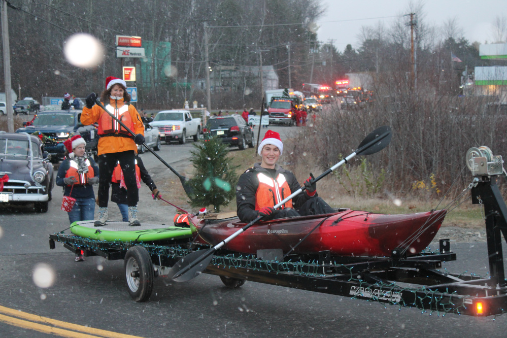 Tanner Webb, with Webb and Sons Paddling, paddles in his holiday float as his mother Laurie Webb stands on top of a paddle boat.