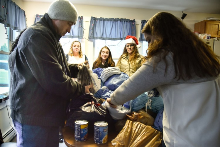 Veteran David Hassle, left front, joins Bread of Life Ministries veteran case manager Elaina George, right front, as they sort through donated food and personal care items. The Christmas donation was organized by Partners for World Health and nursing students from Kaplan University in Augusta.