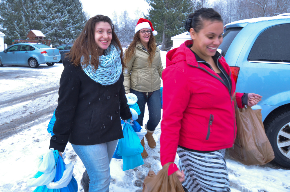 From left, Kaplan University students Liz Ponds, Miranda Costigan and Leleshia O'Neil carry bags of food and personal items for veterans living at the Bread of Life shelter in Augusta.