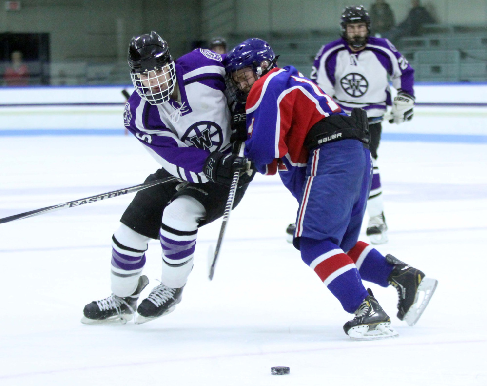Waterville's Dalton Henderson, left, battles for the puck with Messalonskee's Dylan Cunningham during first-period action Thursday at Colby College in Waterville.