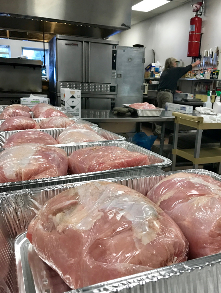 Pans of turkeys wait to go in the oven at the Waterville Elks Lodge kitchen on Friday afternoon as volunteer Fred Snyder works in the background in preparation for the 10th annual Central Maine Family Christmas Dinner on Sunday.