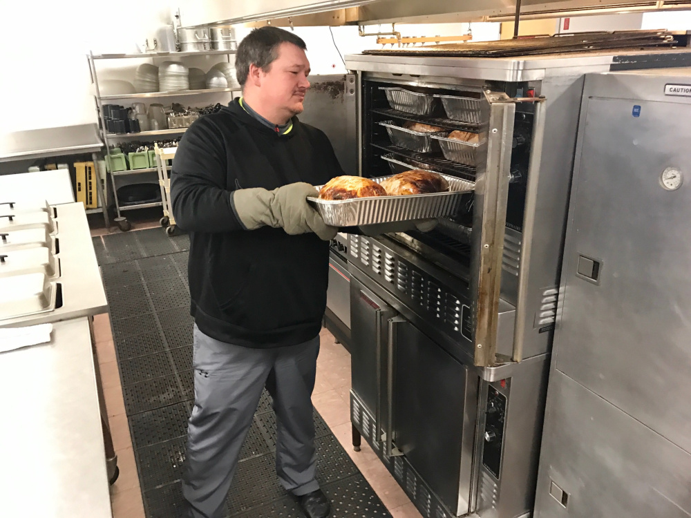 Volunteer Rob Spencer takes out a pan of freshly cooked turkey from the kitchen oven Friday afternoon at the Waterville Elks Lodge, where the 10th annual Central Maine Family Christmas Dinner will be held Sunday.